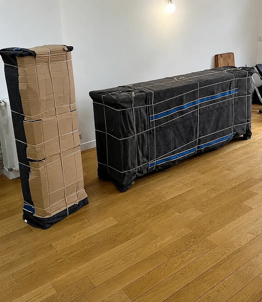 Éléments de mobilier protégés par des couvertures, du carton et des sangles pour un transport