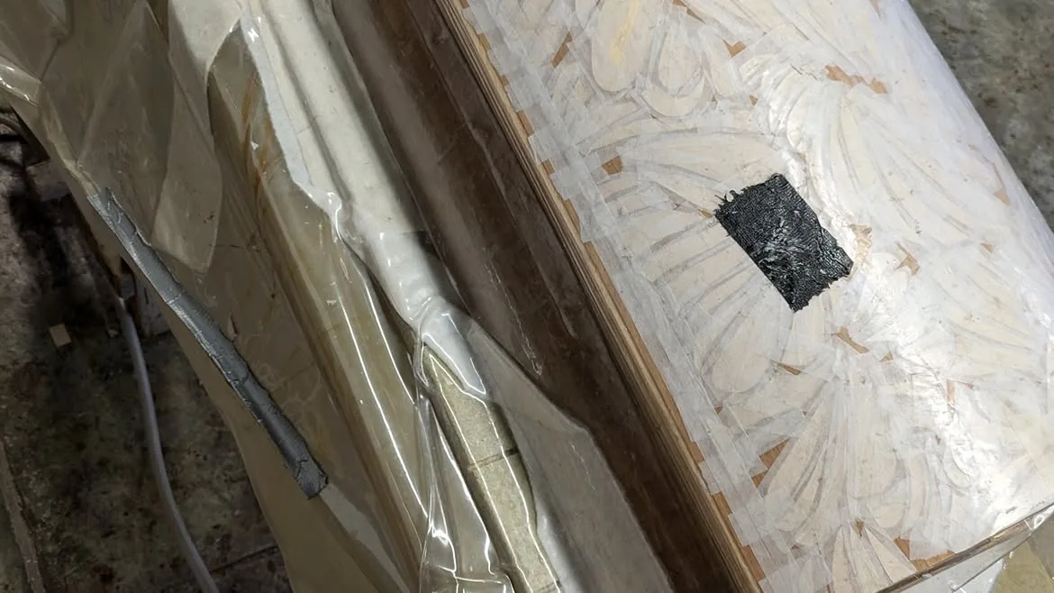 Composition de marqueterie protégée et maintenue sous presse pendant sa fabrication