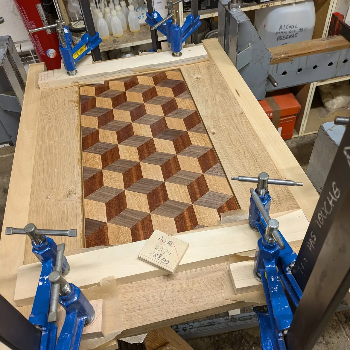 Porte du Kub avec sa marqueterie géométrique maintenue sous serre-joints